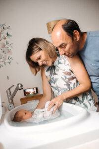 Photo de parents faisant prendre un bain enveloppé à leur bébé